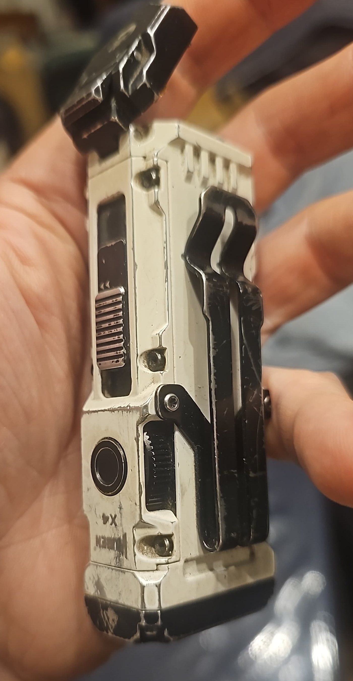 A scuffed white Wuben X4 held in a hand, paint worn through at the edges, battery door open and clip on the side